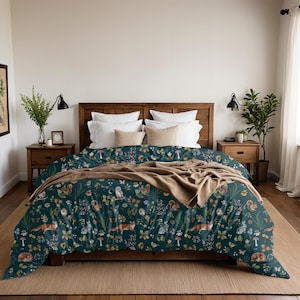 May include: A dark teal duvet cover with a woodland animal pattern, including foxes, owls, and squirrels, with floral and mushroom accents. The bed is made with white pillows and a tan throw blanket. The bed frame is made of wood.