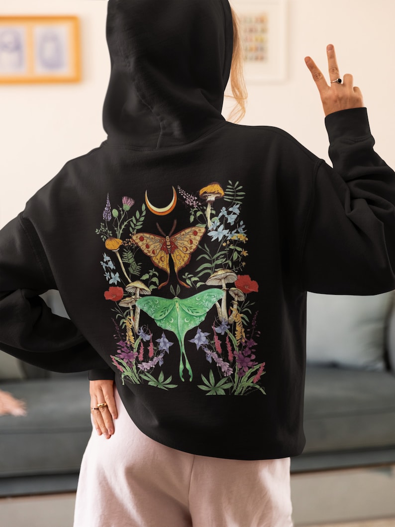 May include: Black hooded sweatshirt with a colorful print of moths, mushrooms, and flowers on the back.
