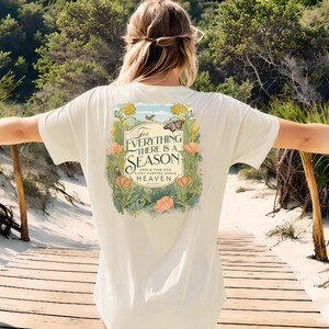 May include: A white t-shirt with a floral design and the text "For Everything There Is A Season And A Time For Every Purpose Under Heaven" printed on the back.