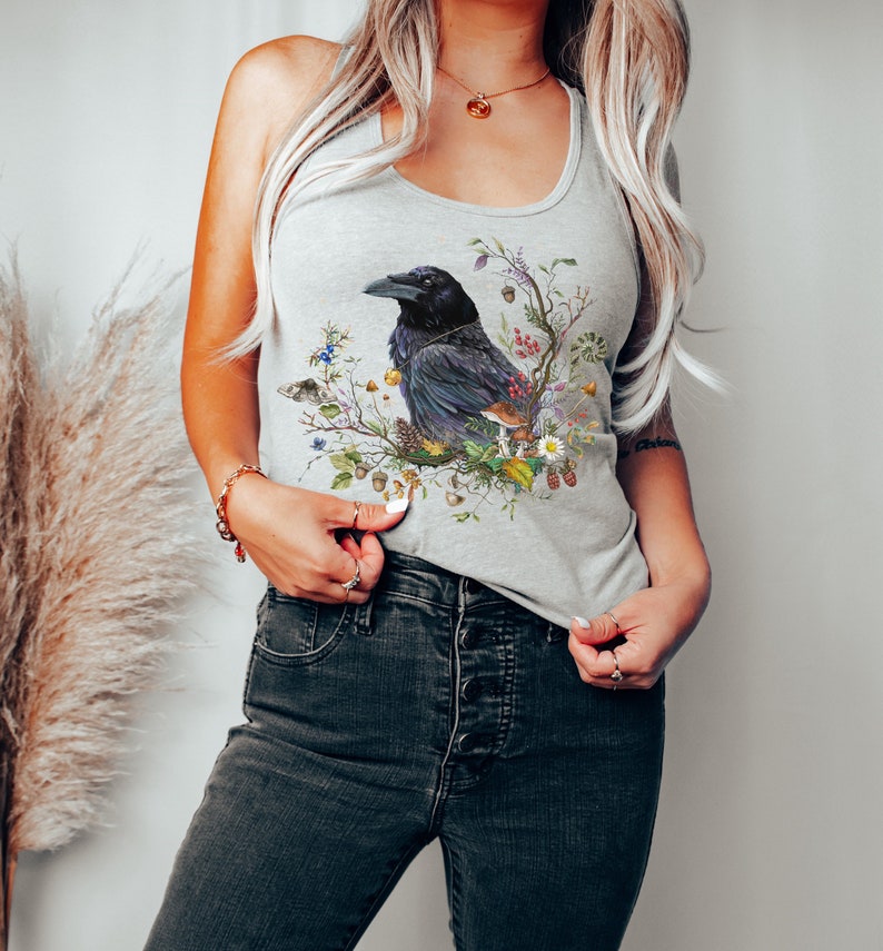 K&ouml;nnte beinhalten: Ein graues Tanktop mit einem schwarzen Raben, umgeben von Blumen und Pilzen. Der Rabe sitzt auf einem Ast mit Bl&auml;ttern und Beeren.