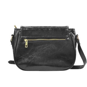 May include: A black leather satchel handbag with a gold zipper and a flap closure. The bag has a shoulder strap.
