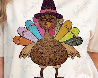 Könnte beinhalten: Ein cremefarbenes T-Shirt mit einem Thanksgiving-Truthahn-Design. Der Truthahn ist braun mit bunten Schwanzfedern und einem Pilgerhut. Das Design ist auf dem T-Shirt zentriert, mit dem Markenlogo oben links.