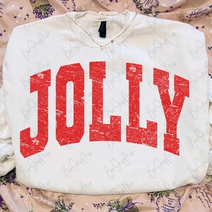May include: White sweatshirt with the word "JOLLY" in distressed red lettering across the front. The sweatshirt has a V-neck and long sleeves. The overall style is casual and festive, perfect for the holiday season.