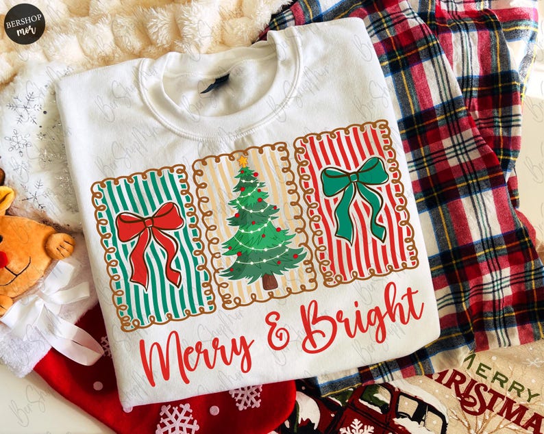 May include: White sweatshirt with a festive design featuring three rectangular panels. The panels display a Christmas tree and bows, with the text "Merry & Bright" in red script. The design is set against a backdrop of plaid fabric and Christmas stockings.