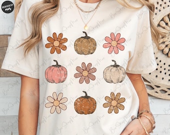 Op de afbeelding: Crèmekleurig T-shirt met een herhalend patroon van pompoenen en bloemen in vintage stijl in bruin-, roze- en perziktinten. Het shirt heeft een ronde hals en korte mouwen. De merknaam "BERSHOP mer" is linksboven zichtbaar.