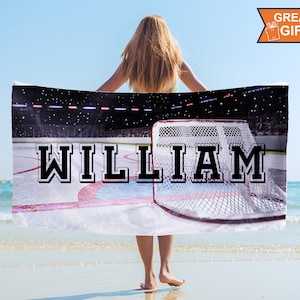 May include: A personalized beach towel featuring a hockey rink design with the name "WILLIAM" in bold, black and white lettering. The towel includes a hockey net and a stadium background. The words "GREAT GIFT" are in the upper right corner.