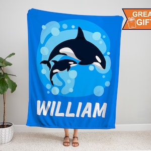 May include: Blue fleece blanket with a white outline of two orcas swimming in a blue circle with white bubbles. The text "WILLIAM" is printed in white below the orcas.