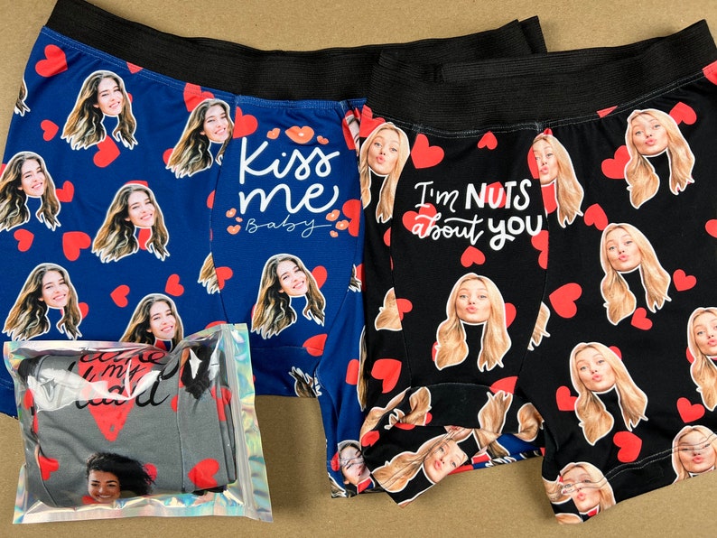 Op de afbeelding: Blauwe en zwarte boxershorts met patronen van gezichten en rode harten. E&eacute;n paar heeft de tekst "Kiss me baby", de andere "I'm nuts about you". Een verpakt paar is ook zichtbaar.