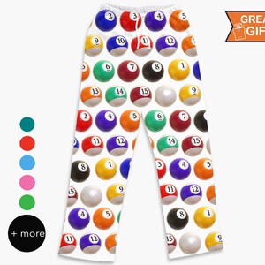 May include: White pajama pants with a repeating pattern of colorful billiard balls, each with a different number. The pants have a drawstring waist and the words "GREAT GIFT" in a banner.