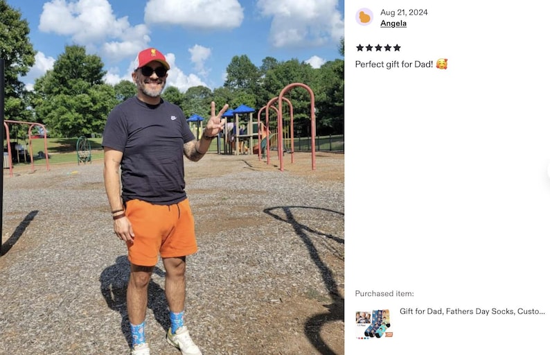 Pode incluir: Uma pessoa vestindo uma camiseta preta, shorts laranja, bon&eacute; vermelho e branco e &oacute;culos de sol, fazendo o sinal de paz em um parque. O c&eacute;u &eacute; azul com nuvens brancas. O texto diz "Perfect gift for Dad!"
