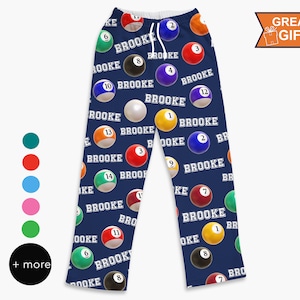 May include: Navy blue pajama pants with a repeating pattern of billiard balls and the name "Brooke" printed in white.
