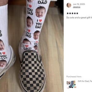 Pode incluir: Meias brancas com um padr&atilde;o repetido de rostos de beb&eacute;, as palavras "I LOVE YOU DAD" e cora&ccedil;&otilde;es vermelhos. As meias s&atilde;o usadas com sapatos slip-on xadrez preto e branco. Uma ideia de presente &uacute;nica e personalizada.