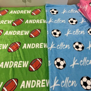 May include: Two personalized fleece blankets, one green with footballs and the name "Andrew" repeated, and one blue with soccer balls and the name "Kellen" repeated.