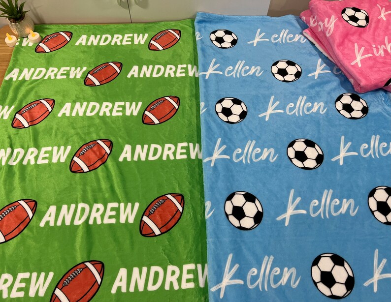 May include: Two personalized fleece blankets, one green with footballs and the name "Andrew" repeated, and one blue with soccer balls and the name "Kellen" repeated.