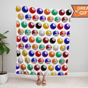 May include: A white blanket featuring a repeating pattern of billiard balls, each with a different number and color. The blanket has a "GREAT GIFT" graphic in the upper right corner.