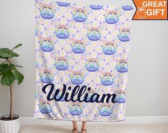 May include: A soft, plush blanket with a repeating pattern of rainbow peace signs and white daisies on a light purple background. The blanket has the name "William" written in a navy blue cursive font.