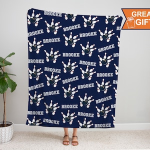 May include: A navy blue fleece blanket with a repeating pattern of bowling pins and balls. The name "BROOKE" is printed in white with a red outline on each bowling ball.