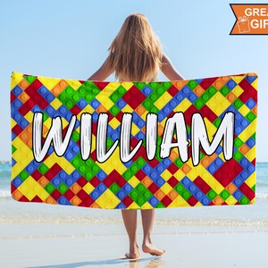 May include: A colorful beach towel with a pattern of colorful building blocks and the name "WILLIAM" printed in white.