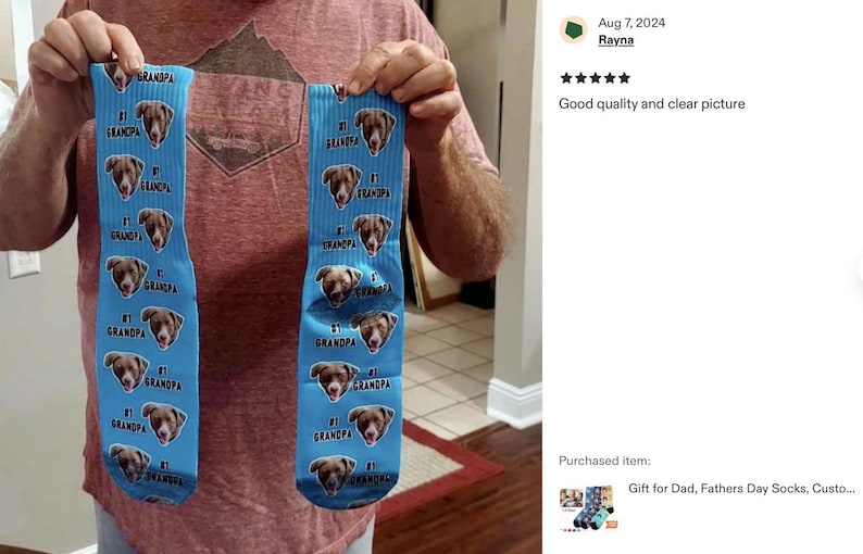 Pode incluir: Um par de meias azul claro com um padr&atilde;o repetido do rosto de um c&atilde;o e as palavras "#1 Grandpa". As meias s&atilde;o levantadas, mostrando o design. As meias s&atilde;o um presente para o Dia dos Pais.