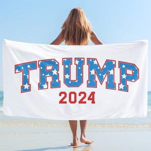 May include: White beach towel with the text "TRUMP 2024" in red and blue letters with a star pattern. The letters are in a collegiate font.