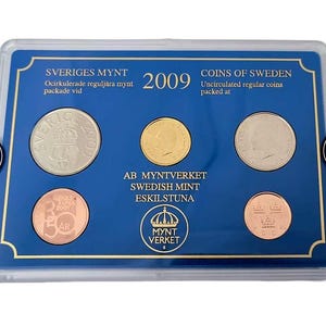 May include: A collection of uncirculated Swedish coins from 2009, presented in a clear plastic case with a blue background. The case includes text in Swedish and English, such as "Sveriges Mynt" and "Coins of Sweden."