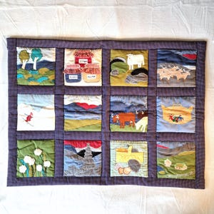 Peut inclure: Une courtepointe patchwork faite à la main avec une bordure à pois bleu foncé. La courtepointe présente douze carrés, chacun représentant une scène rurale différente, notamment des paysages, des animaux et des aliments. Les carrés sont de différentes couleurs, dont le vert, le bleu, le rouge et le jaune.