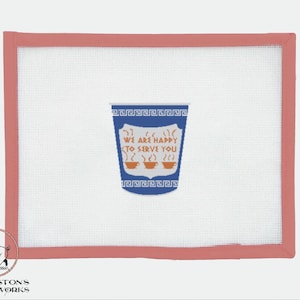 Peut inclure: Une broderie au point d'aiguille sur toile bleue et blanche avec une bordure rouge. Le motif est une tasse à café à emporter stylisée avec le texte "We are happy to serve you" et trois tasses à café fumantes.