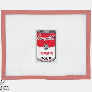 以下が含まれることがあります： トマトスープと書かれた赤と白のキャンベルスープ缶。缶は赤い縁取りのある白い背景の上に置かれています。