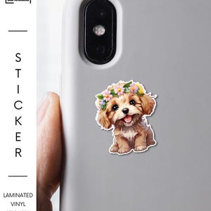 May include: A laminated vinyl sticker featuring a smiling puppy wearing a floral crown. The sticker is affixed to a gray phone case. The brand name "BarkRebels" is visible on the left side of the image.
