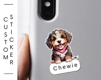 May include: A custom laminated vinyl sticker featuring a smiling cartoon puppy wearing a pink bandana. The puppy's name, "Chewie," is printed on a white oval. The sticker is on a gray phone case.