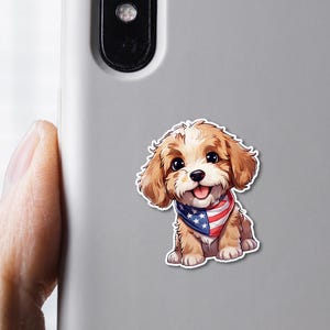 May include: A sticker of a cartoon puppy with brown and white fur, wearing a red, white, and blue bandana. The puppy is smiling with its tongue out. The sticker is on a gray phone case.