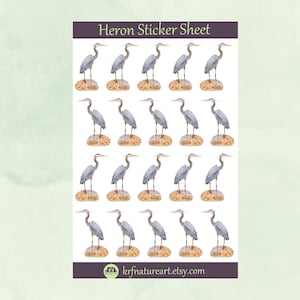 May include: A sticker sheet featuring multiple watercolor illustrations of herons. Each heron is depicted in shades of gray and blue, standing on a small, textured, tan-colored mound. The sheet is labeled "Heron Sticker Sheet."