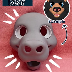 May include: A gray bear fursuit base with a large, open mouth and two large eye holes. The base is made of foam and is ready to be painted and customized. The image also shows an example of a finished fursuit head, with black fur and blue eyes. The text "Bear" and "Example" are visible in the image.
