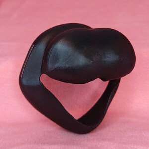 May include: A black 3D printed face mask with a curved design. The mask has a large opening for the nose and mouth.