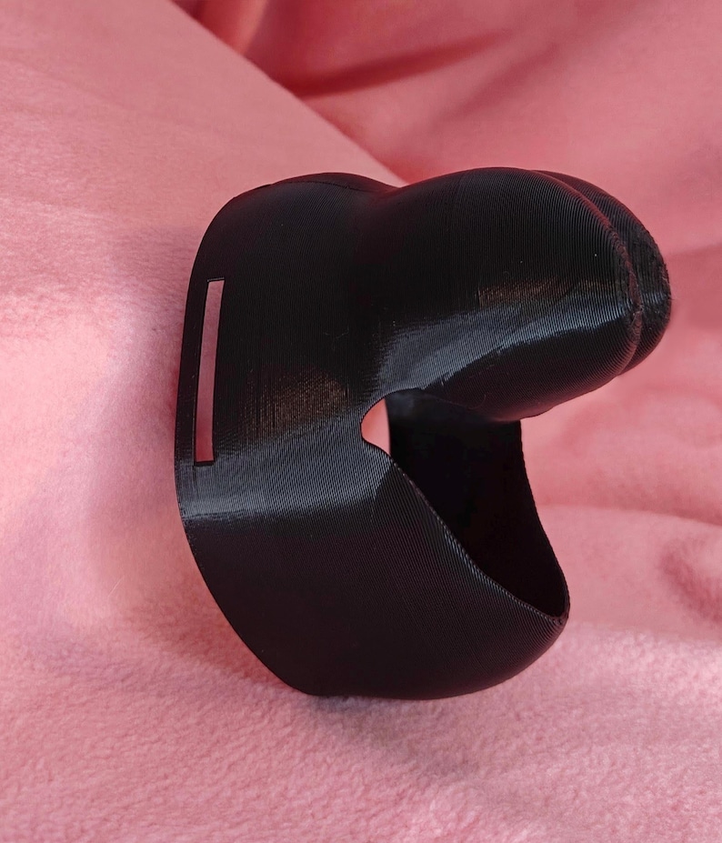 May include: A black 3D printed object with a curved shape and a small rectangular opening. The object is made of a smooth, matte material.
