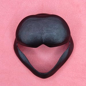 May include: A black 3D printed helmet with a textured surface. The helmet has a rounded top and a pointed chin.