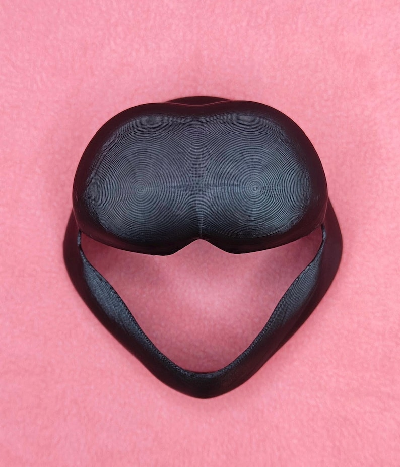 May include: A black 3D printed helmet with a textured surface. The helmet has a rounded top and a pointed chin.