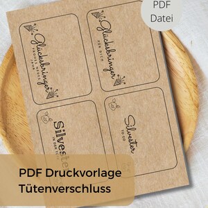 Puede incluir: Hoja de papel kraft con cuatro etiquetas rectangulares, cada una con texto negro y elementos decorativos. Las etiquetas presentan frases como "Glücksbringer" y "Silvester". Una superposición marrón claro dice "PDF Druckvorlage Tütenverschluss".