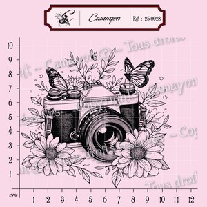 May include: Black and white illustration of a vintage camera surrounded by flowers, leaves, and butterflies on a pink background. The image includes the text "Camayon" and "Ref: 25-0028". The camera is approximately 7 cm wide.