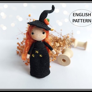 Puede incluir: Patrón de crochet para una pequeña muñeca bruja con cabello naranja, un vestido negro con estrellas y un sombrero de bruja negro con una calabaza naranja en la parte superior. El patrón está escrito en inglés.
