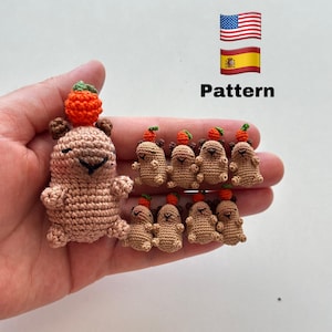 May include: Crocheted bear and miniature bear figures in shades of brown, each with a small orange pumpkin on their heads. The word "Pattern" is displayed with the American and Spanish flags.