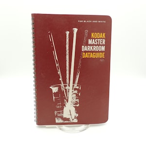 May include: A red spiral bound book with the title "Kodak Master Darkroom Dataguide" in yellow text. The book is for black and white photography and features a graphic of a glass beaker with three brushes inside.