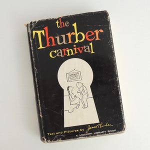May include: A vintage hardcover book titled "The Thurber Carnival" with a black cover. The title is in yellow and red lettering. The cover features a keyhole design with a cartoon illustration. Text at the bottom reads "Text and Pictures by James Thurber."