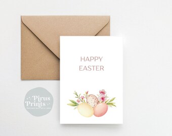 Pode incluir: Um cartão branco com o texto "Feliz Páscoa" em letras cor-de-rosa. O cartão apresenta uma ilustração em aquarela de três ovos de Páscoa em tons pastel com flores cor-de-rosa e folhas verdes.