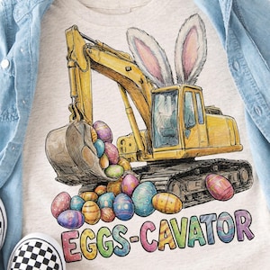May include: A light gray t-shirt featuring a yellow excavator with bunny ears and a bucket full of colorful Easter eggs. The text "EGGS-CAVATOR" is printed below the excavator in rainbow colors. A light blue denim shirt and checkered slip-on shoes are also in the image.