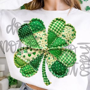 Może przedstawiać: Biała bluza z dużym, patchworkowym wzorem koniczyny w różnych odcieniach zieleni. Koniczyna wykonana jest z różnych wzorzystych tkanin, w tym grochów i kratki vichy. Szare litery mówią "do not copy".