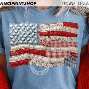 Op de afbeelding: Een lichtblauw T-shirt met een patchwork ontwerp van de Amerikaanse vlag. De vlag heeft witte sterren op een blauw veld en rood-witte strepen met bloemen- en ruitpatronen. De tekst "DAVINCIPRINTSHOP" is zichtbaar bovenaan.