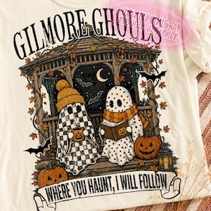 May include: A cream-coloured t-shirt featuring a graphic of two ghosts in a gazebo. One ghost wears a chequered pattern and a beanie, holding a mug. The other ghost wears a scarf and reads a book. Text reads GILMORE GHOULS and WHERE YOU HAUNT, I WILL FOLLOW.