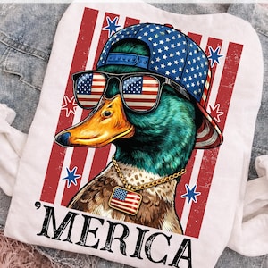 May include: White t-shirt featuring a duck wearing sunglasses with American flag lenses, a blue cap with white stars, and a gold chain with an American flag pendant. The word 'MERICA is printed below the duck.