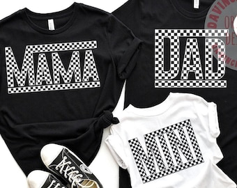 May include: Black t-shirts with white checkered text that reads "MAMA", "DAD", and "MINI". A pair of black sneakers and a white hat are also in the image. The shirts are likely family matching apparel.